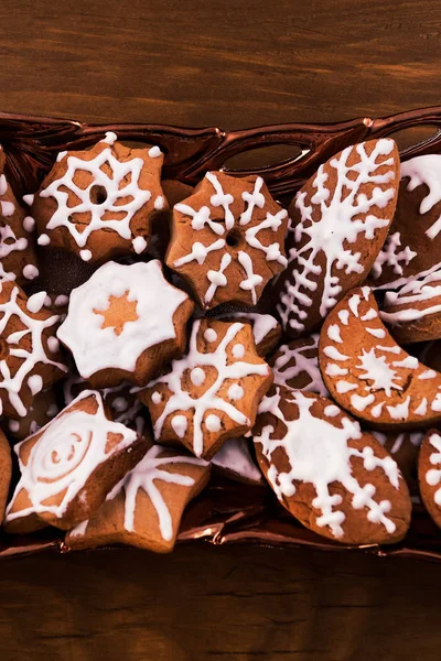 Cookies decorated with icing sugar in a glass plate on a wooden background.