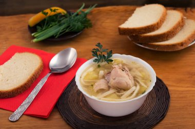 Yemek tavuk çorbası, dilimlenmiş beyaz ekmek, maydanoz ve soğan twigs, ahşap arka plan.