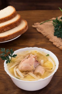 Ahşap arka plan üzerine açık et suyu, beyaz derin kasede et parçaları ile tavuk erişte.