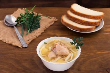 Tavuk çorbası erişte ve patates, ekmek, ahşap arka plan dilimlenmiş taze maydanoz ile.