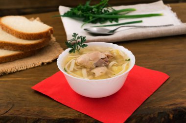 Tavuk erişte garson, içinde et parçaları temizleyin suyu, Yeşil taze maydanoz, ahşap arka plan üzerinde kırmızı kağıt peçete.