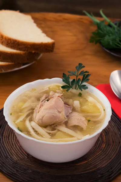 Maydanoz sapı ile beyaz bir kase tavuk şehriye çorbası.