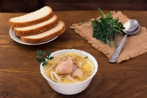 Ahşap arka plan açık et suyu, beyaz kase içinde et parçaları ile tavuk erişte.