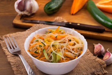 Pirinç Noodle ile beyaz bir derin kapta, keten peçeteye metal çatal dilimlenmiş sebze.