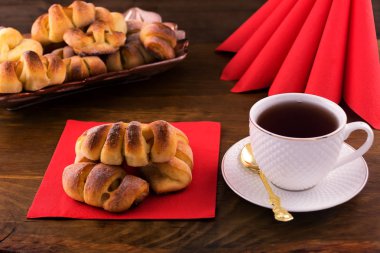 Doldurma, ahşap arka plan üzerinde beyaz Porselen Kupa, kırmızı peçeteler çay meyve şekerli tatlı.