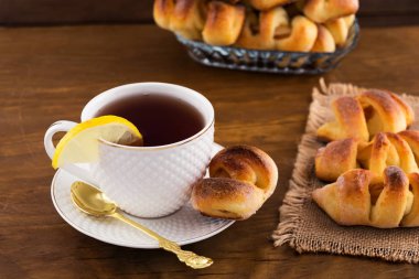 Doldurma, çay bir dilim limon beyaz bir kupa, ahşap arka plan ile meyve ile hamur işleri.