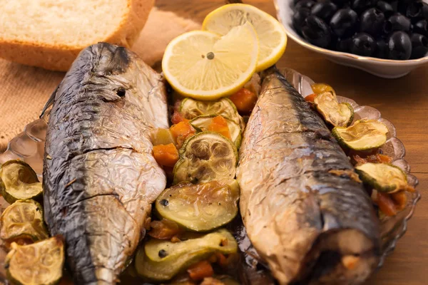 Uskumru, tamamen pişmiş sebzeler, limon dilimleri ve biber ile.