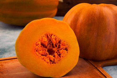 Bir ahşap tahta üzerinde kesme olgun kabak ile pürüzsüz bir parçası kesilmiş.