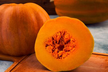 Yarı ahşap arka plan üzerinde parlak turuncu ciltlerinin dilimlenmiş kabak.