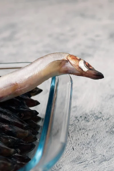 海小鱼在玻璃容器的边缘 木制背景 — 图库照片