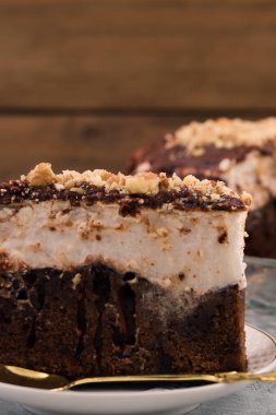 Çikolatalı kek. Yakın çekim. Beyaz ve kahverengi tabaka. Dikey. Ahşap arka plan.