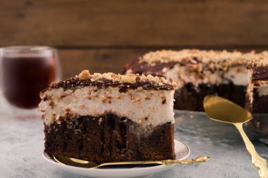 Çikolatalı pasta dilimlenmiş. Beyaz ve kahverengi tabaka. Yer fıstığı ile serpin. Tatlı yemekleri. Ahşap arka plan.