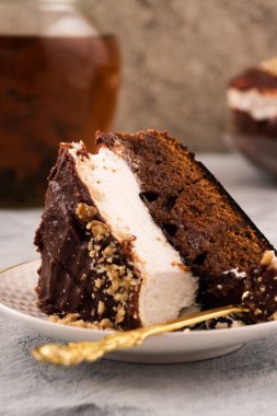 Bir plaka üzerinde çikolatalı kek parçası. Kahverengi ve beyaz tabaka. Tatlı kaşığı. Dikey. Açık renkli.