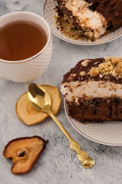 Çikolata tatlı plakaları. Çay kaşığı kurutulmuş meyve dilimleri. Çay beyaz kupa. Dikey. Açık renkli.