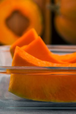 Dilimlenmiş kabak parçaları. Olgun portakal eti. Pişirme için cam kap.