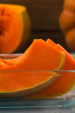 Bir cam kase kabak portakal parçaları. Vejetaryen yiyecekler. Çiğ sebze. Turuncu hamuru. Dikey.