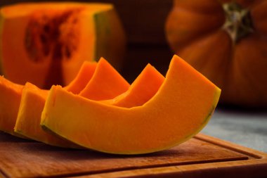 Bir ahşap tahta üzerinde olgunlaşmış kabak dilimleri. Turuncu hamuru. Açık renkli.