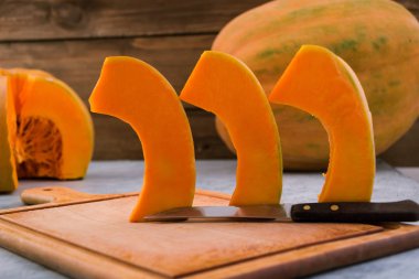 Kabak dilim kavurma için satır bulunmaktadır. Mutfak tahta kesme. Olgun meyve portakal eti. Çiğ sebze. Açık renkli.