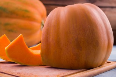 Turuncu büyük balkabağı. Dilimler kesin. Mutfak tahta kesme. Açık renkli. Meyve portakal hamuru. Olgun sebze.