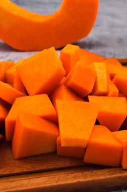 Mutfak kurulu dilimlenmiş kabak parçaları. Çiğ sebze hazırlanması. Vejetaryen yiyecekler. Olgun meyve portakal eti.