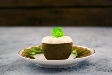 Yarım kivi beyaz jöle ile. Yeşil jelatin küp. Dilimler beyaz bir tabağa dilimlenmiş. Açık renkli.