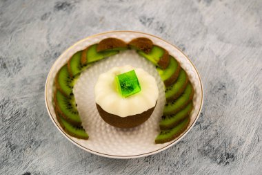 Güzel tatlı. Yarım kivi ve beyaz jöle. Yeşil jelatin bir küp. Olgun Kivi dilimleri beyaz bir tabağa dilimlenmiş. Açık renkli.