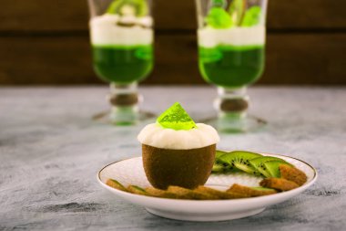 Beyaz bir plaka üzerinde yeşil ve beyaz jelatin ile yarım olgunlaşmış kivi. Açık renkli.