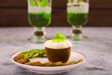 Güzel egzotik tatlı. Yarım kivi beyaz jöle ile. Jelatin bardak. Kivi dilimleri beyaz bir tabağa dilimlenmiş. Açık renkli.