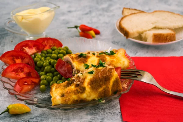 Bir rulo et doldurma ile yumurta omlet. Yeşil bezelye. İtalyan mutfağı - brizoli bir tabak. Açık renkli.