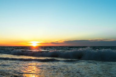 Günbatımı sahil üzerinde. Kıyı dalgalar. Ufukta bulutlar. Güzel manzara.