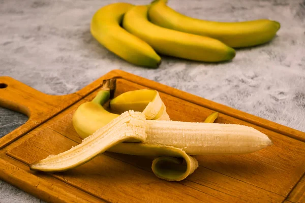 Uma Banana Inteira Meio Descascada Fundo Madeira Frutos Exóticos — Fotografia de Stock