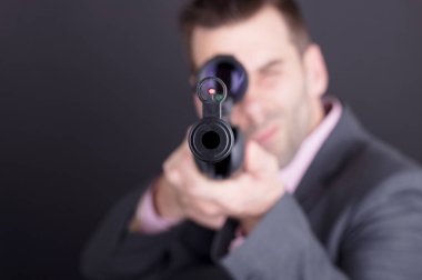 Tüfek ve kapsamı ile takım elbiseli adam