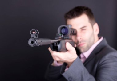 Tüfek ve kapsamı ile takım elbiseli adam