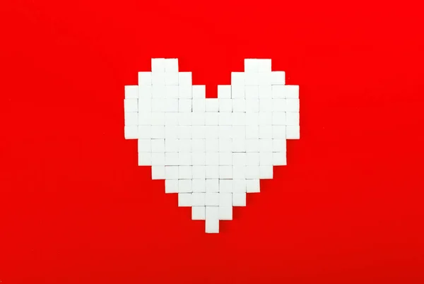 Heart of sugar cubes, red background — Stock Photo, Image