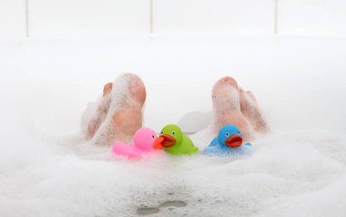 Parlak beyaz bir küvette erkeklerin ayakları, seçici bir şekilde ayak parmaklarına odaklanır.