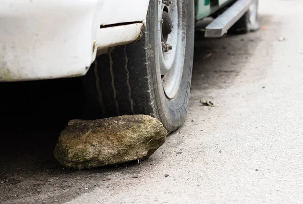 Large stone behind a wheel of a car — Stock Photo, Image