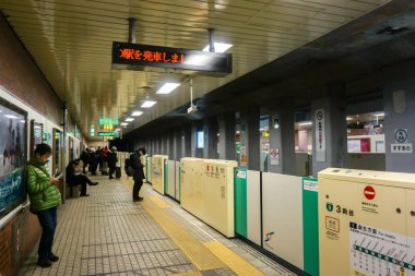 Osaka, Japonya 17 Şubat 2018: Japon erkekleri ve turist bekleyen metro Metro İstasyonu Osaka, Japonya.