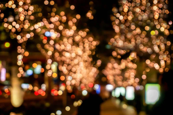Blurred and bokeh of LED refection lighting decorate on trees with city night life in Osaka, Japan.