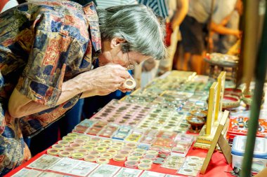 Lampang, Thailand, 24 Mart 2018: Tay yaşlı adam küçük Büyüteç Buda muska bir göz atın, dikkatle eski semt pazarı içinde kullanma.