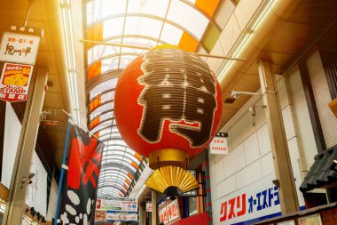 Osaka, Japonya, 19 Şubat 2018: Büyük kırmızı fener Kuromon Ichiba taze Pazar, Osaka, Japonya güneş patlaması arka plan ile girişinde asılı Japon kağıt süslemeleri.