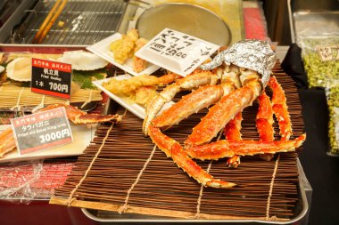 Osaka, Japonya, 19 Şubat 2018: Closeup Barbekü Kral Yengeç bacakları ve tarak üzerinde bambu Japon adı ve fiyat etiketleri ile ızgara. Satılık Kuromon street Market, Osaka, Japonya.