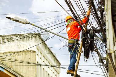 Arama Görünümü kablo onarım teknisyeni olan eski şehir ve mavi gökyüzü arka planda bina ile elektrik kutubun ağ bağlantı kabloları ve telleri satırları düzeltmek için.