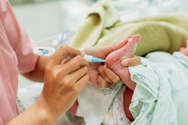 Elinde tutan ve hasta onay glikoz NICU wards, kanında hazırlamak için yeni doğan bebek ayaklar üzerinde Accu-Chek Fastclix (kan ve glukoz kontrolü için iğne kalem) bıçak kullanarak çocuk hemşiresi.