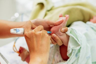 Pediatrik elinde tutan ve hasta onay glikoz NICU wards, kanında hazırlamak için yeni doğan bebek ayaklar üzerinde kan ve glikoz onay bıçak için iğne kalem kullanarak hemşire.