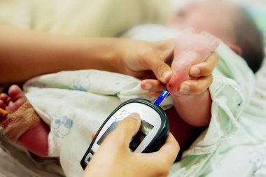 Çocuk hemşiresi, el ele tutuşup kan ve glikoz metre ile levha kullanılarak hasta yeni doğan bebek kan touch kontrol ve check-up glikoz NICU wards, kanında ayaklar.