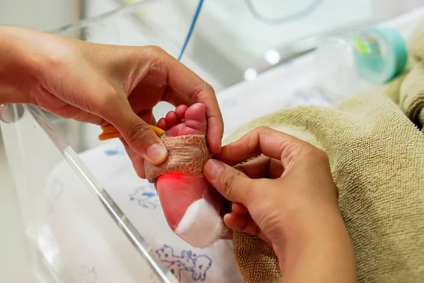 Çocuk hemşiresi tıbbi yapıştırıcı kullanarak elinde sopa ve kandaki oksijen ölçmek ve hastanede NICU wards, kriz yeni doğan bebek organları için oksijen değer ayak görmek için kayış alçı.