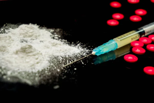 Portre ve tıbbi iğne ve beyaz toz kırmızı hapı tıp ile plastik şırıngada kırpma siyah arka plan üzerine izole etmek. Eroin ve amfetamin ya da Alkolizim varsayalım.