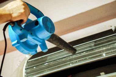 Portre ve ürün el elektrik üfleyiciler su ile yıkama sonrası soğutucu Klima bobin önünde sıcak hava üfleme tutan elektrik onarım teknisyeni.
