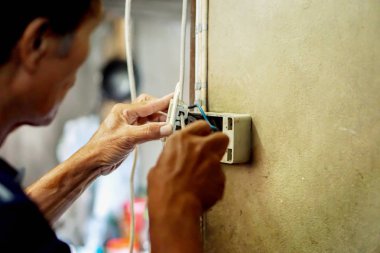 Eski bina duvar ve bulanık arka plan üzerinde elektrik prizine sabitleme Closeup elektrik onarım teknisyeni.