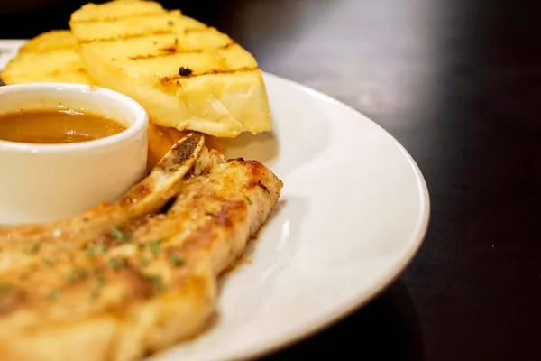 クローズ アップのレストランの黒いテーブルの白いセラミック プレートにペッパー ソース Bone 豚肉ステーキとニンニク パンをトリミングし — ストック写真